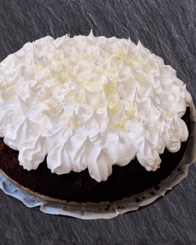 Laktosefri chokoladekage pyntet med royal icing og revet hvid chokolade.