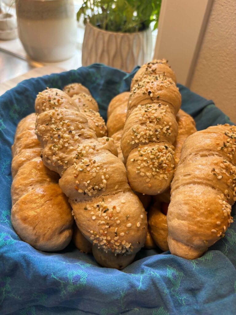 Hjemmelavede pølsehorn serveret i en kurv, hvor nogle er drysset med hampefrø og sesamfrø.
